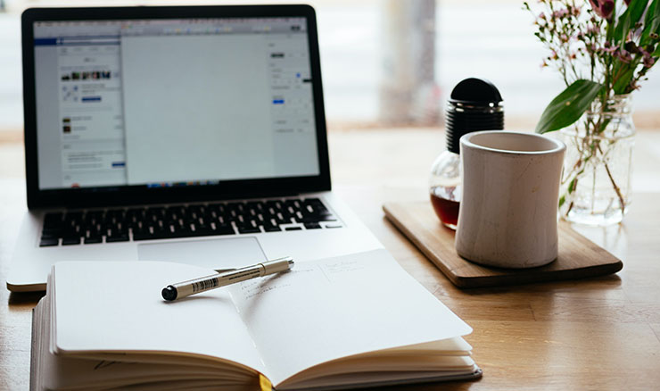 Computer with open book and pencil.