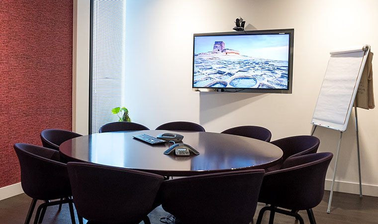 Empty small meeting room with video conference equipment.