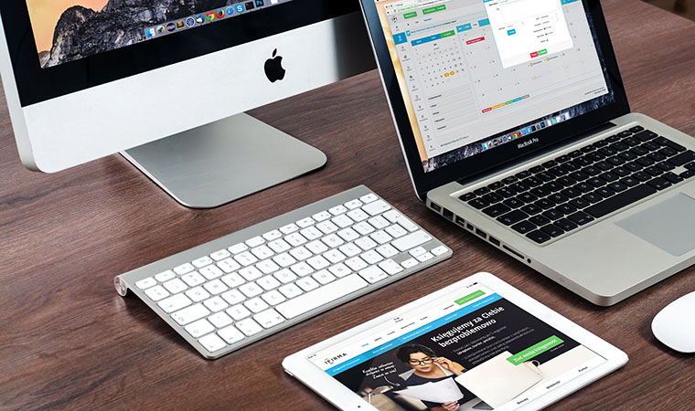 Desktop, laptop, and tablet computers on a desk.