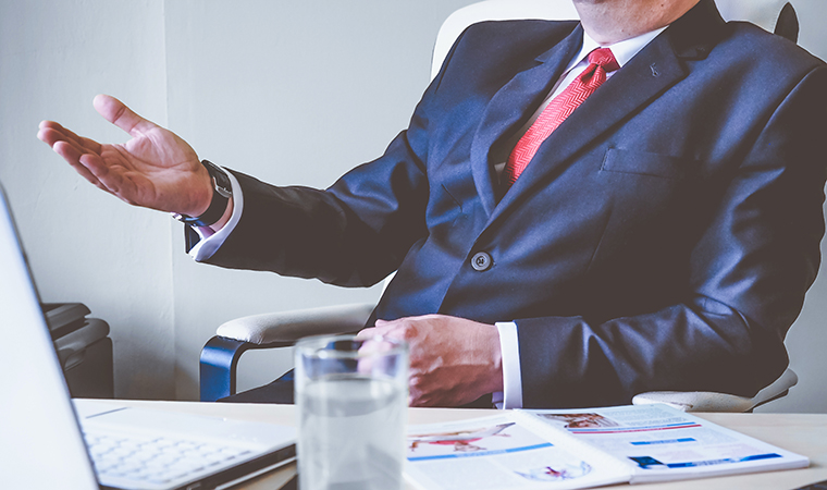 Man in suit sitting behind desk.