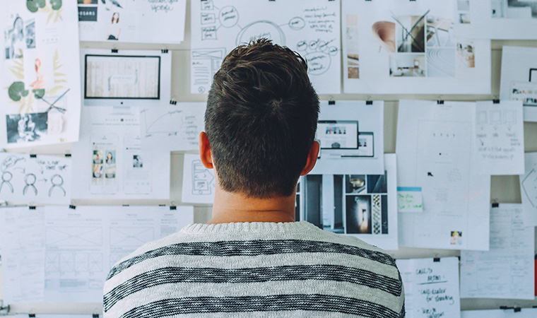 Man looking at papers tacked to wall.