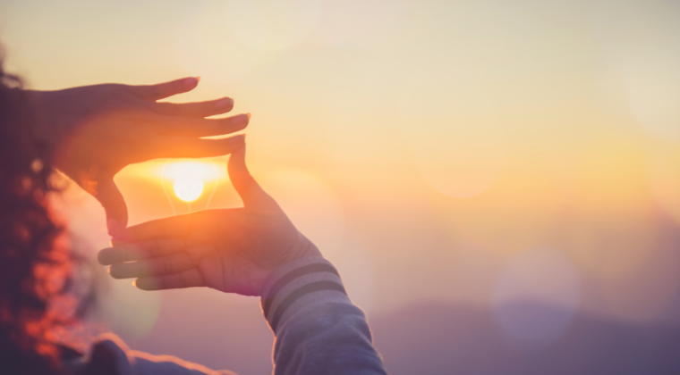 Graphic depicting two hands framing the sun.