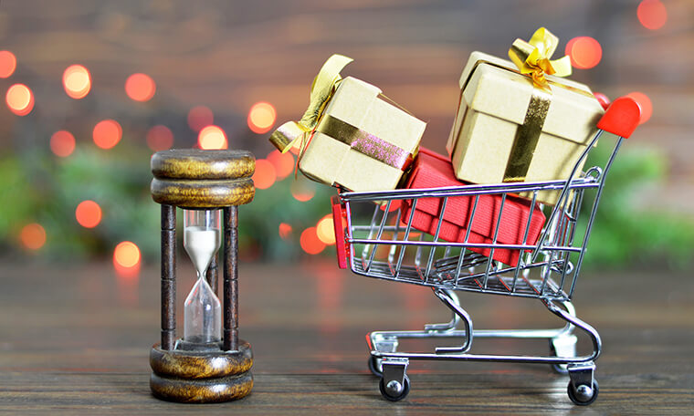 Photograph depicting the holiday rush as a cart full of miniature gifts running into an hourglass.