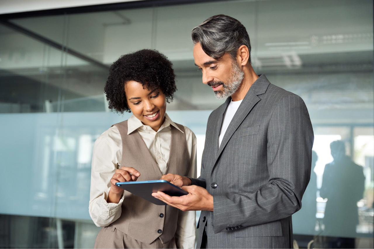 two business executives collaborating on a tablet in a modern office