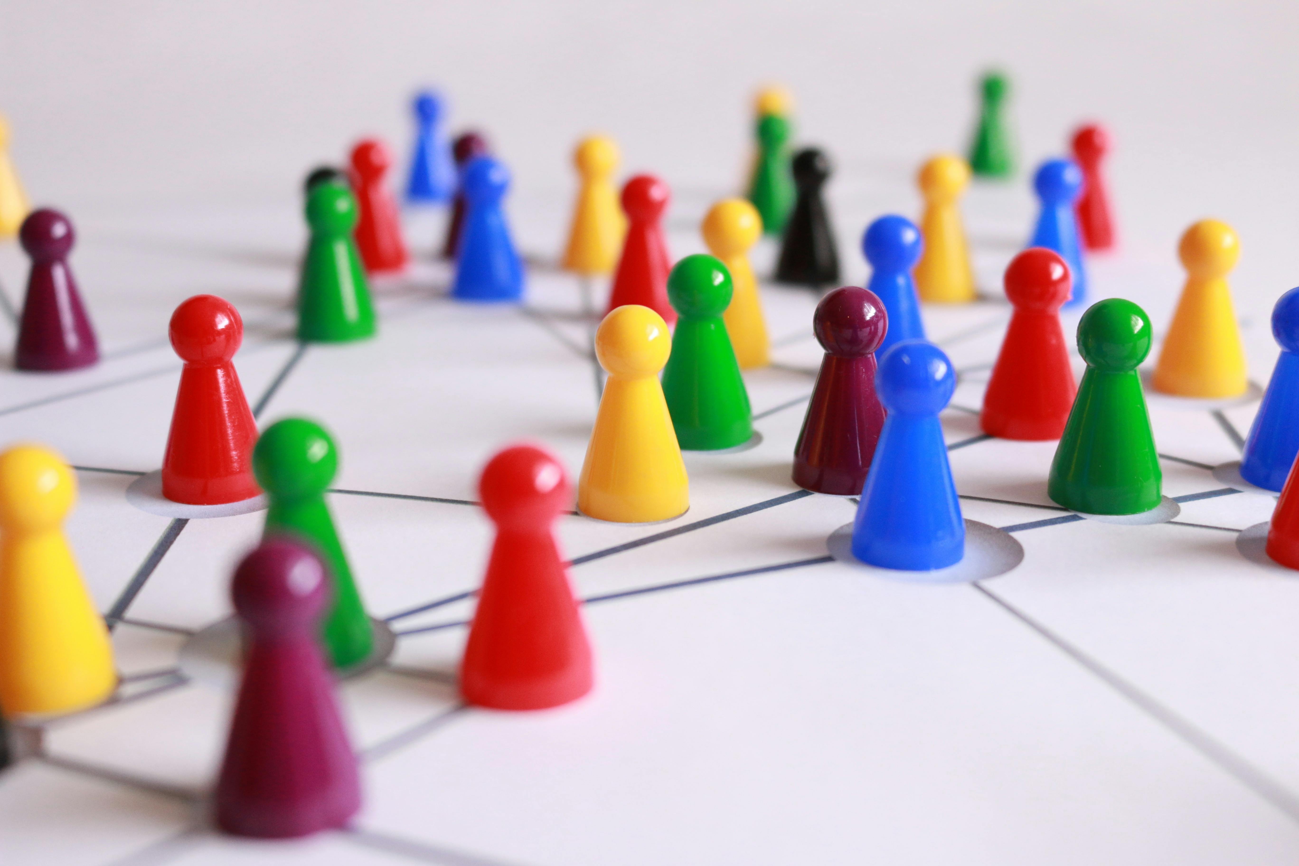 Close-up of colorful plastic cones in yellow, green, red, and brown arranged on a white-lined surface, symbolizing organization and strategic planning.