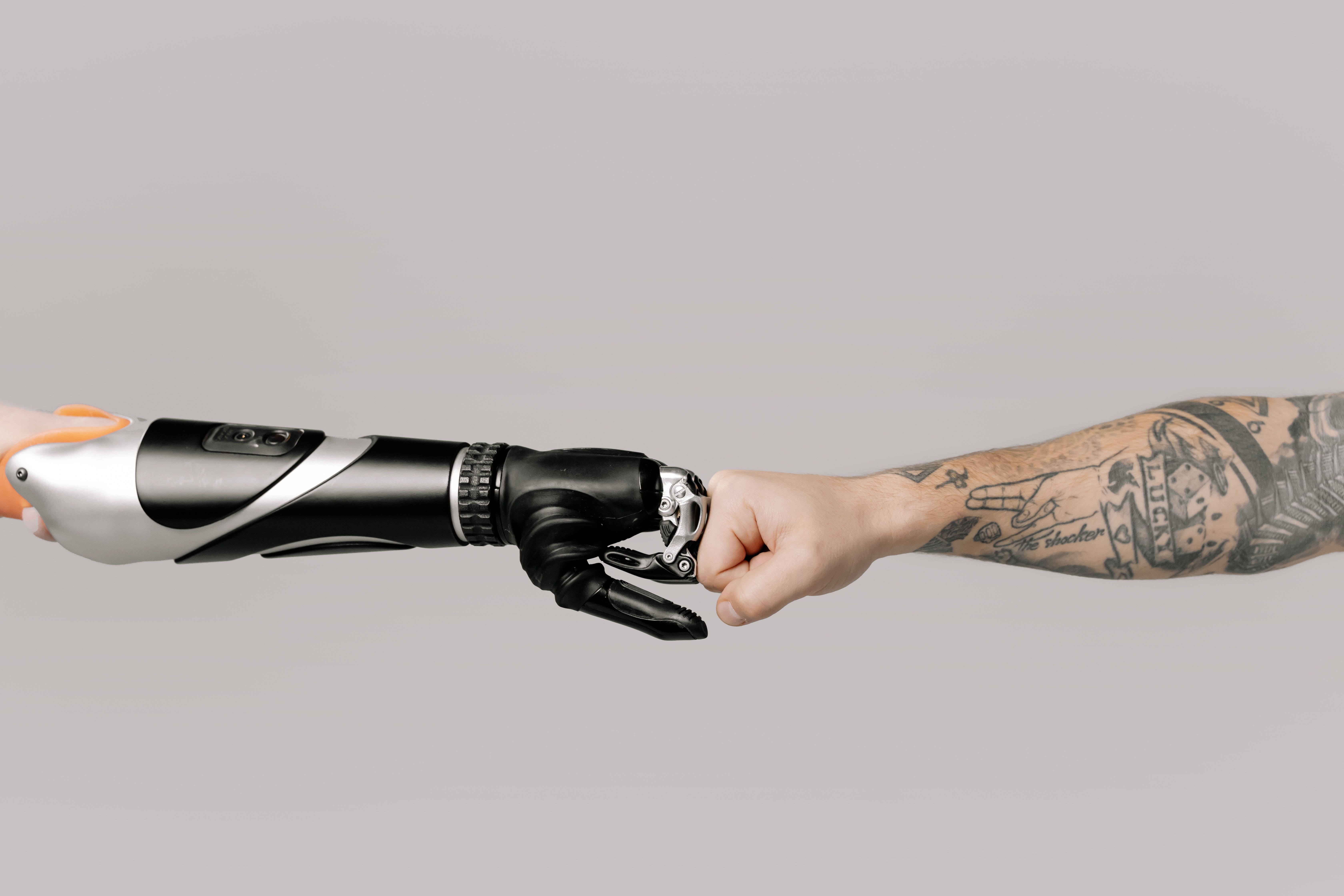 Close-up of a fist bump between a human and a robotic hand, symbolizing collaboration between AI and humans in business transformation.