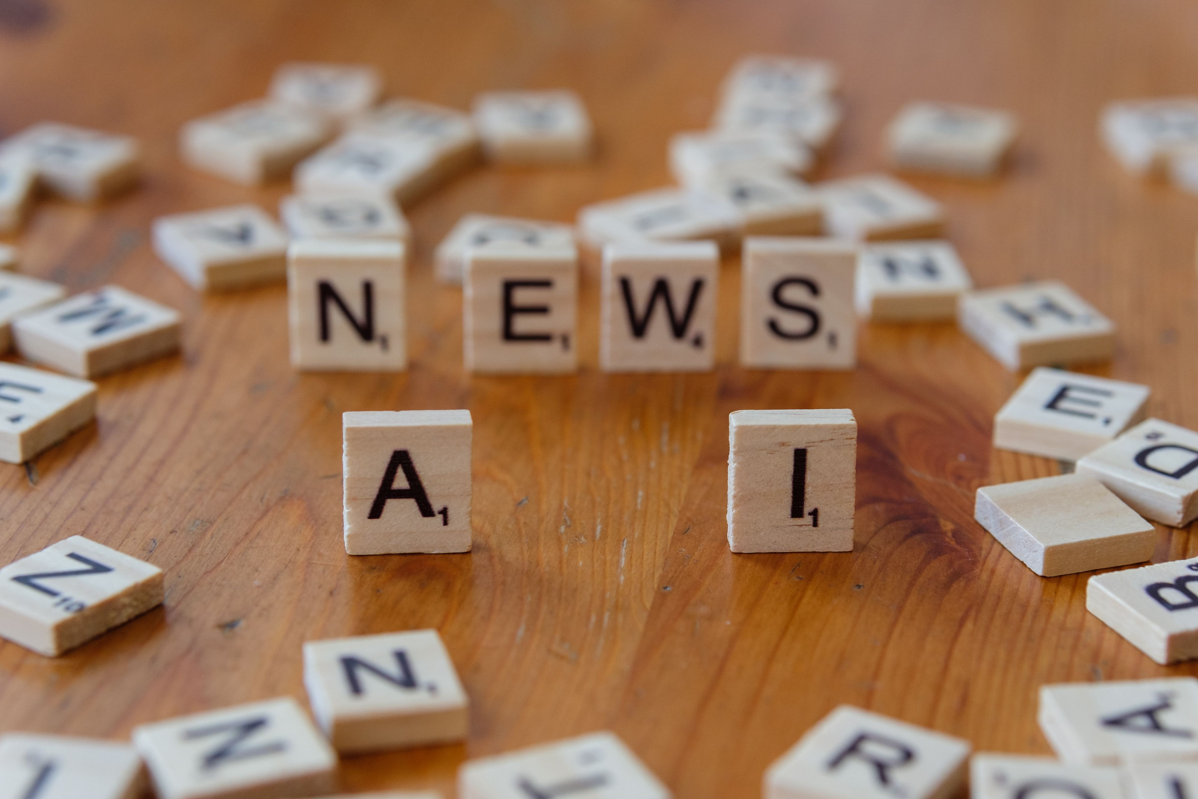 Scrabble tiles spelling "AI News" on a wooden surface, symbolizing advancements in artificial intelligence and its impact on communication.