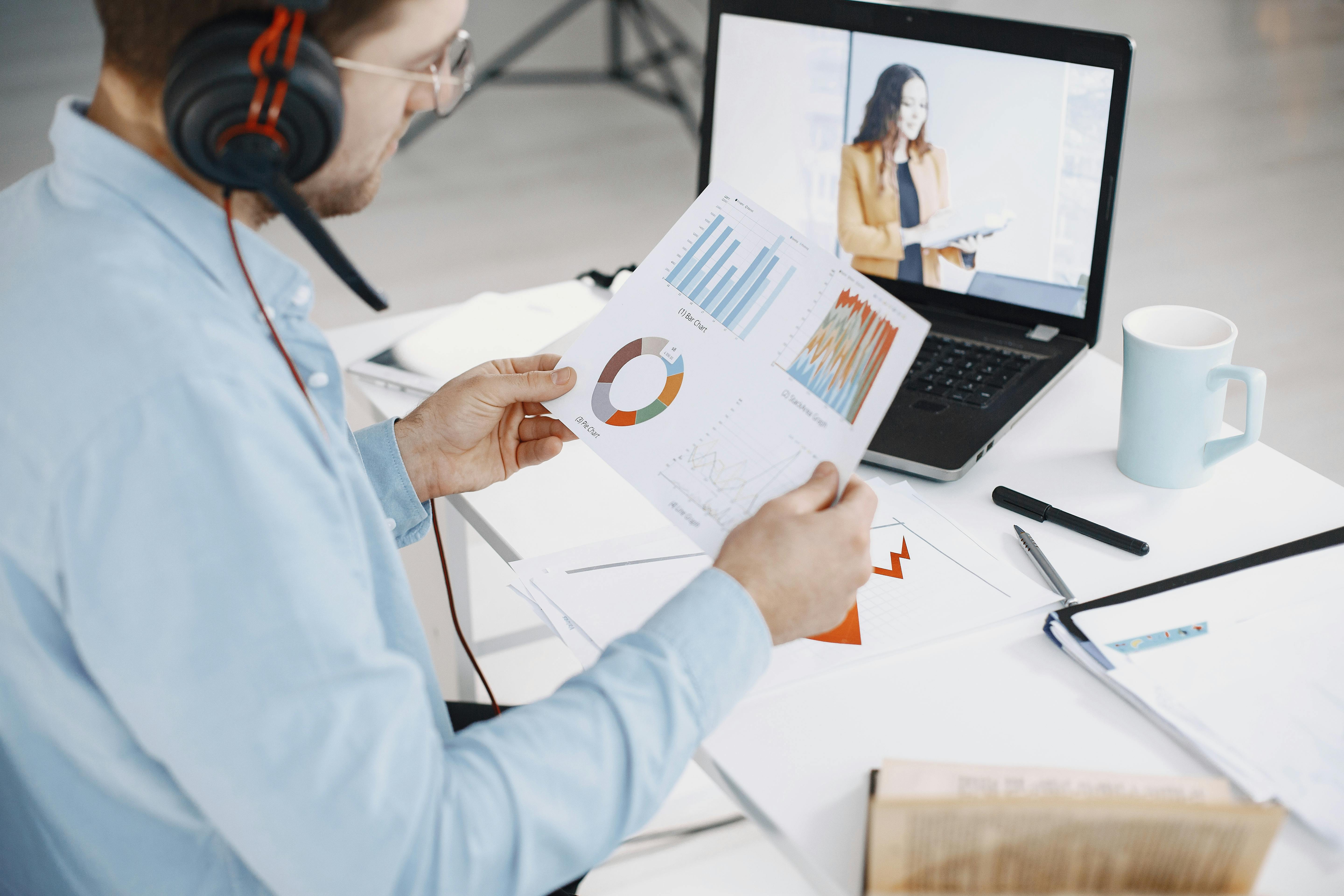 A businessman analyzing charts and data on a desk, symbolizing digital transformation and innovation in remote contact centers.