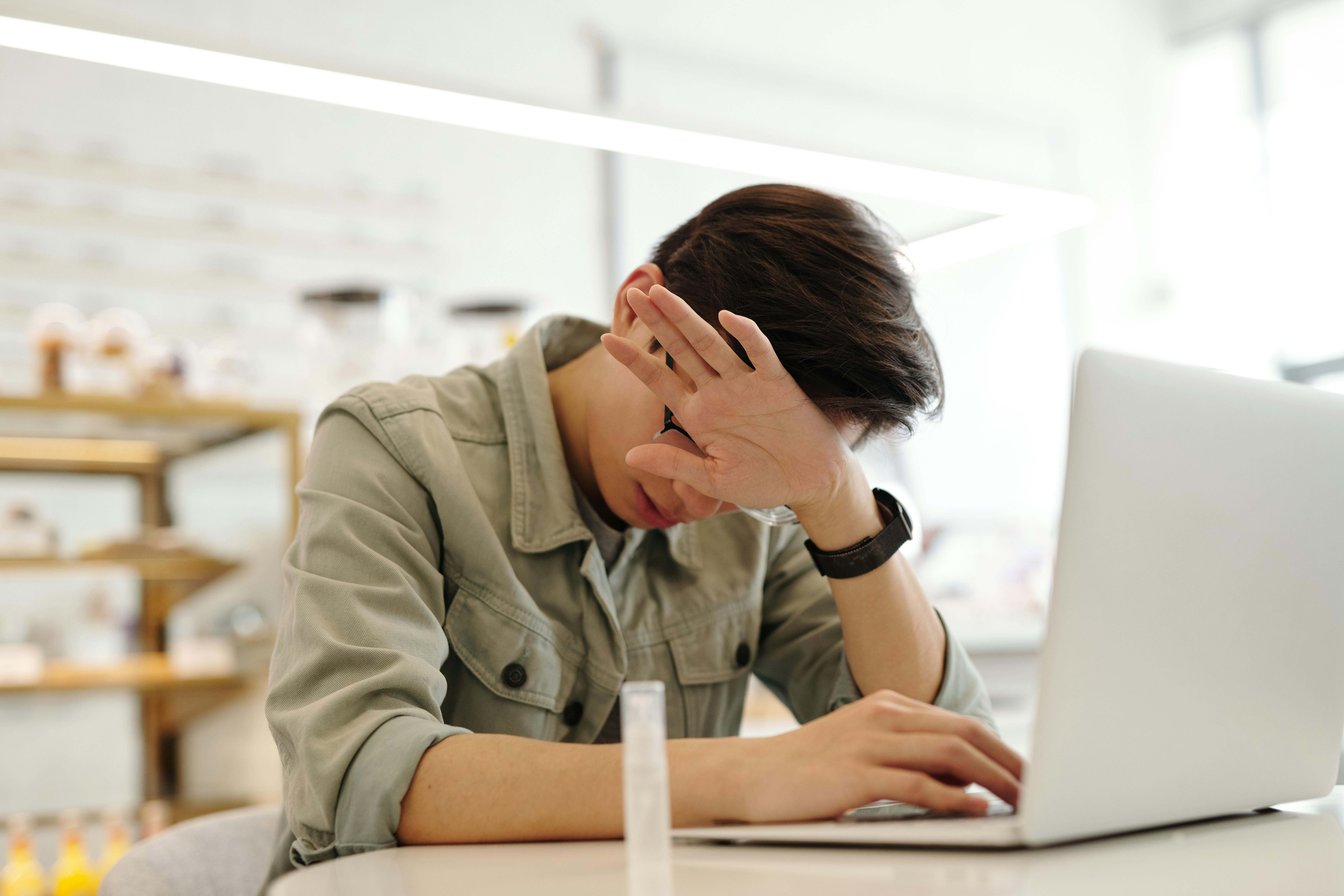 stressed out man sitting at laptop at work