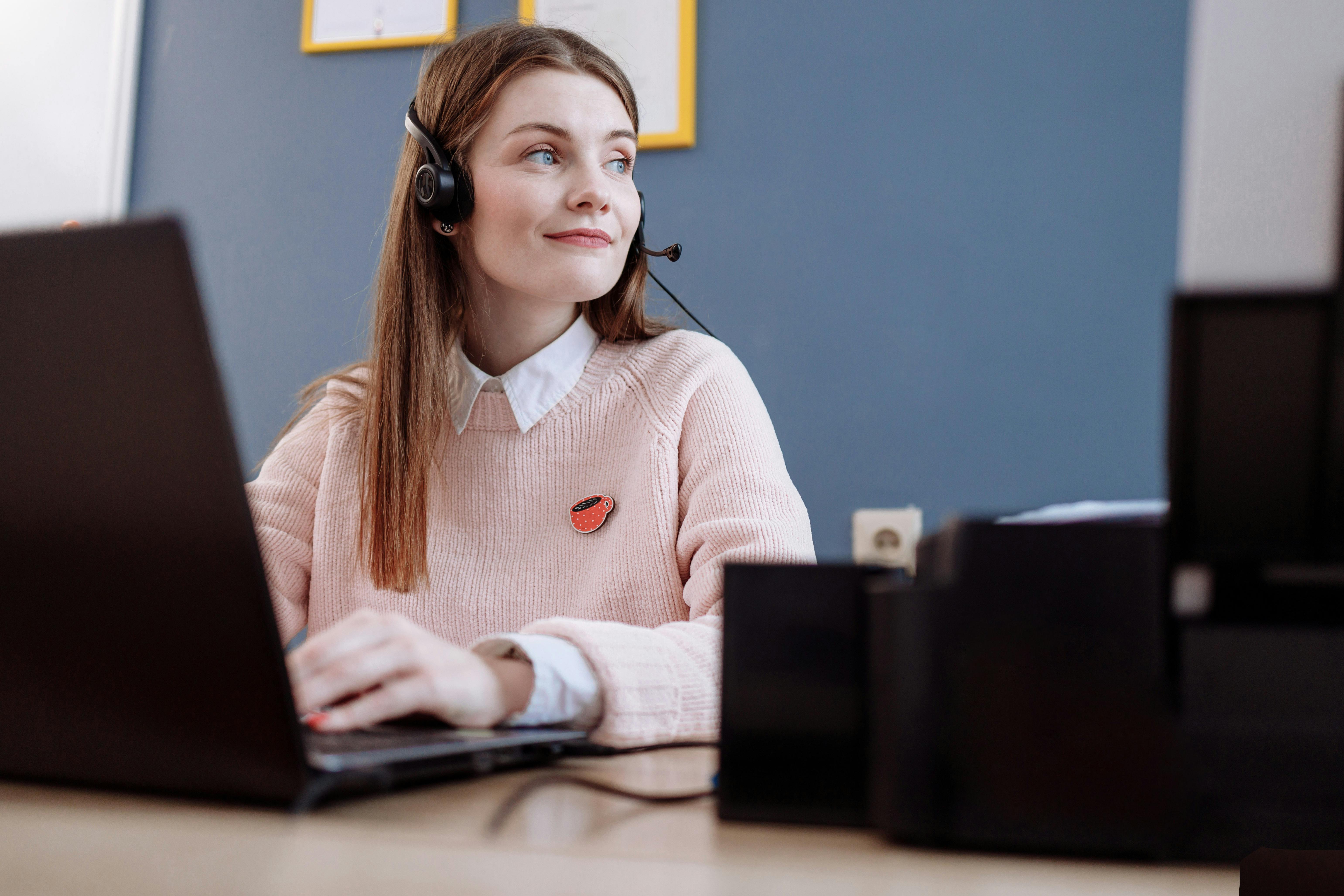 a woman sitting at her laptop wearing a call center headset at work
