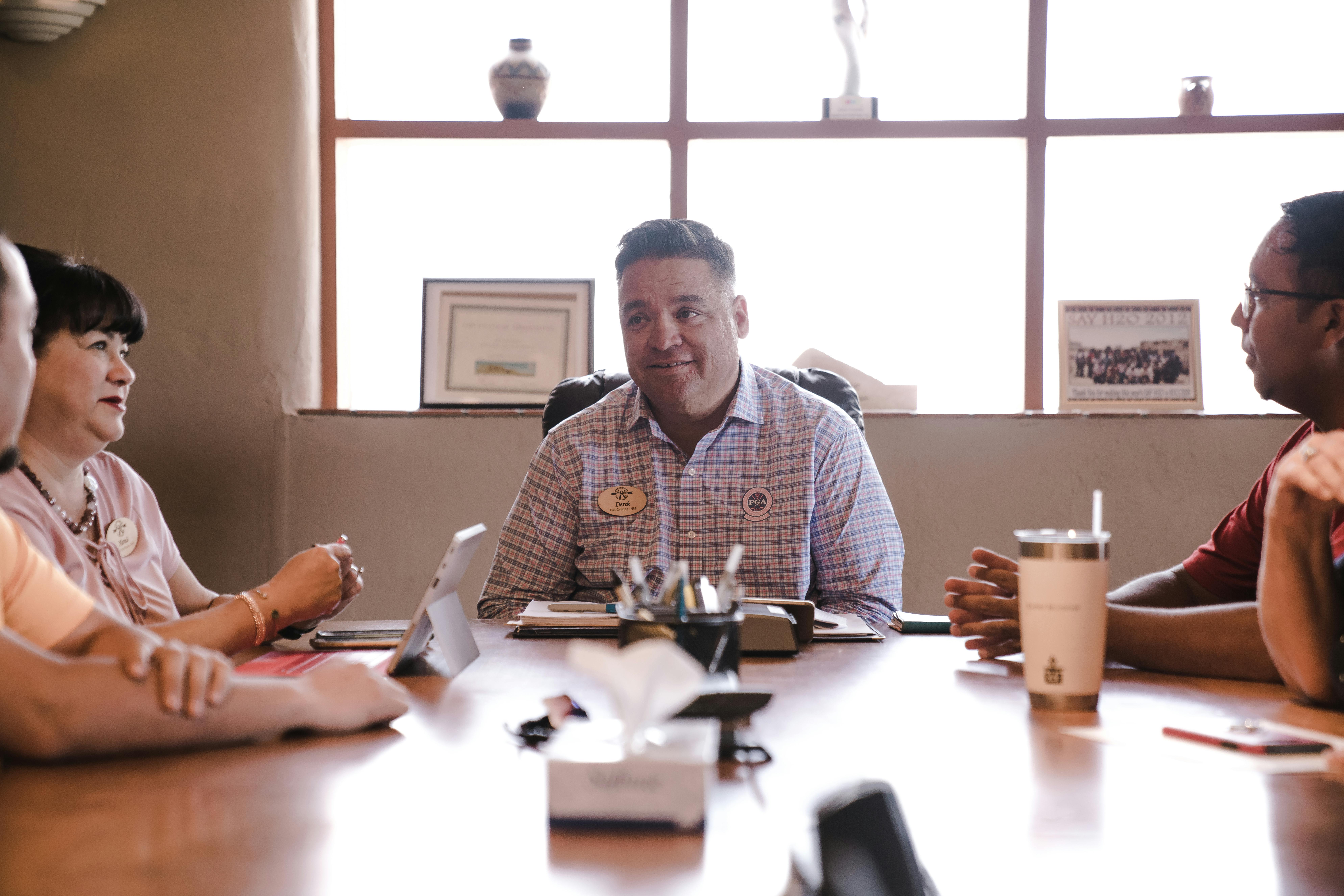 A group of professionals seated around a boardroom table, engaged in discussion and collaboration
