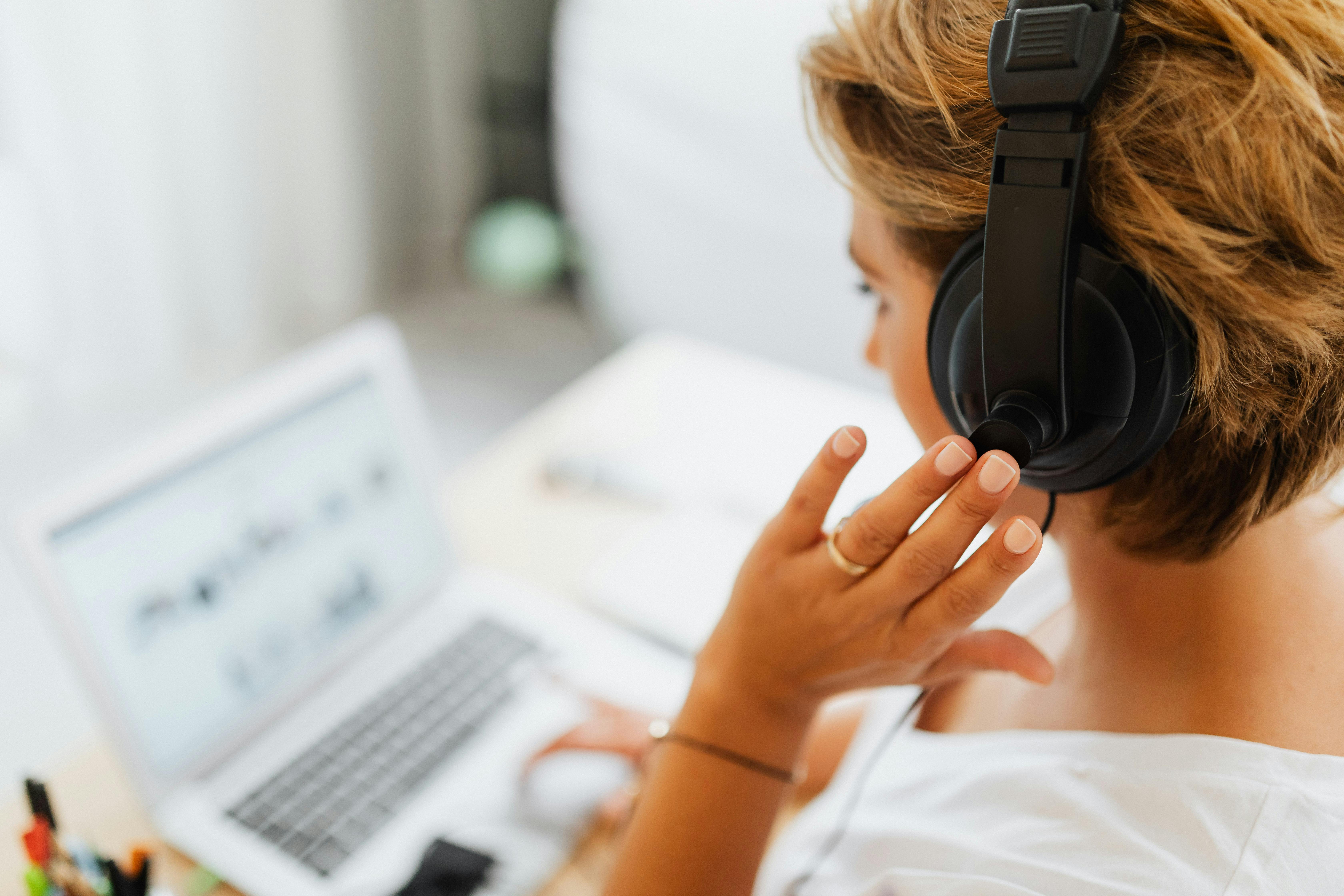 A customer service representative wearing a white shirt holds black headphones while smiling, symbolizing friendly and attentive customer support.