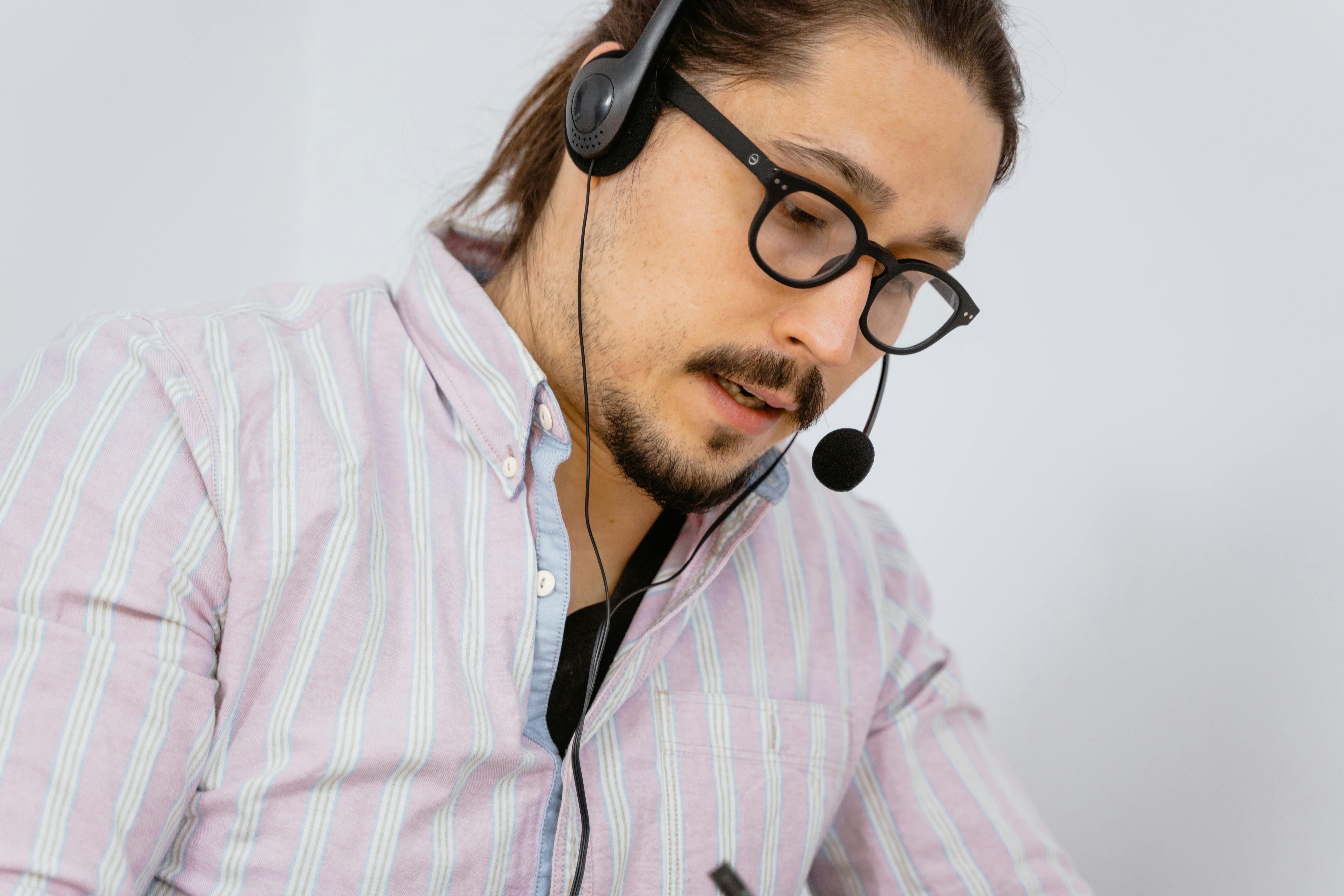 close up of a male contact center agent wearing glasses and headset taking a call