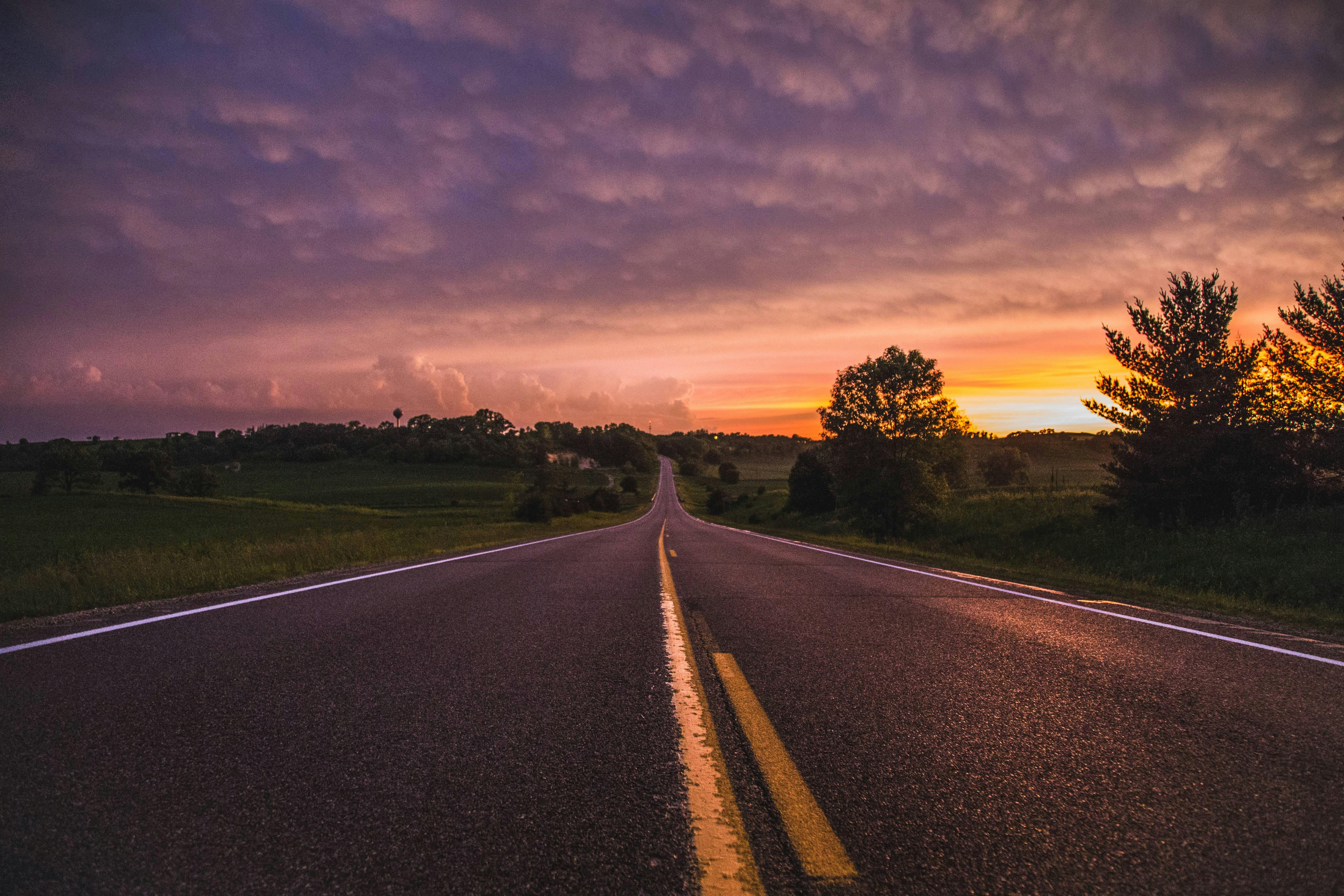 Empty road surrounded by grass fields during golden hour, symbolizing life's journey and the path of self-discovery and growth.