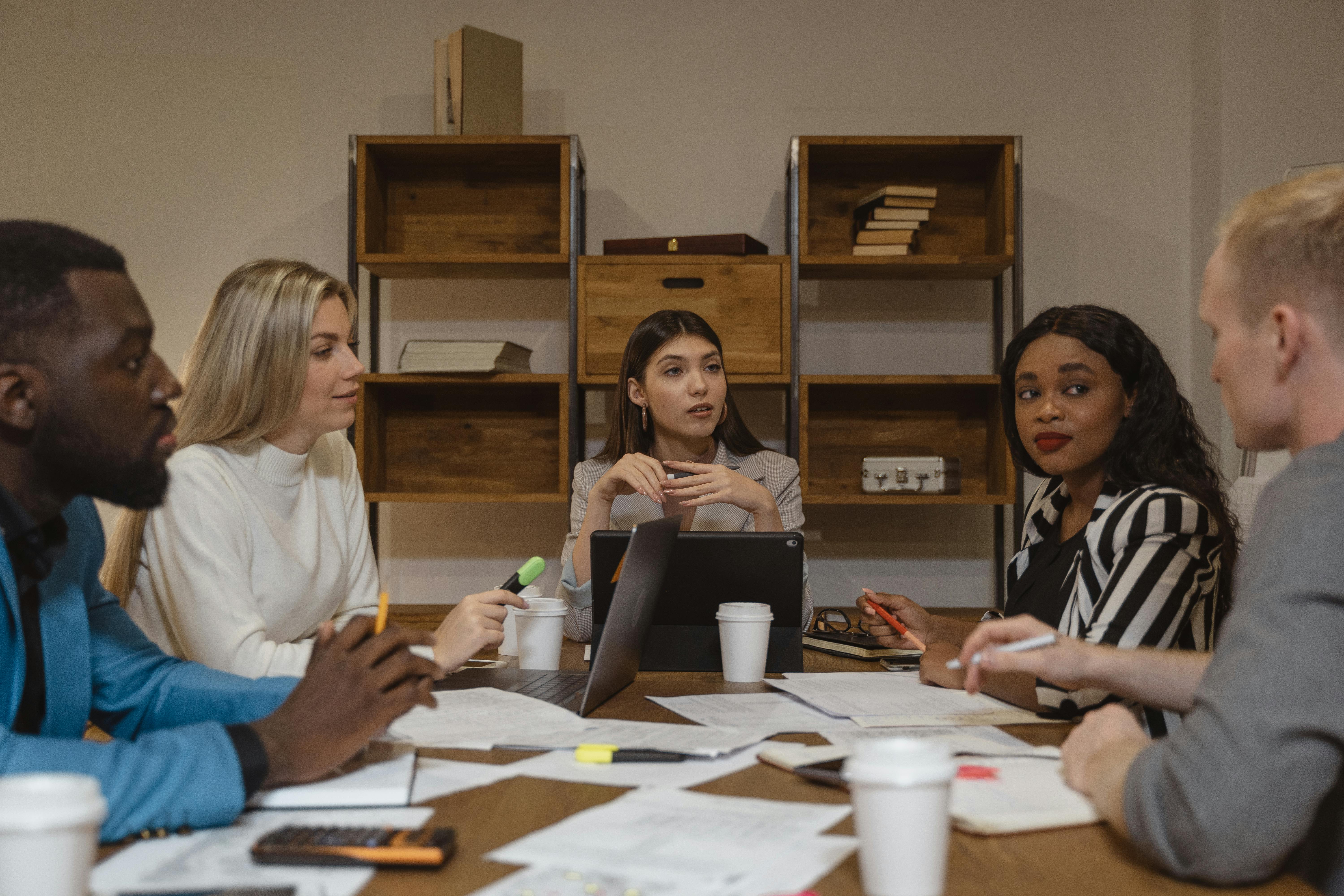 A diverse group of professionals engaged in a collaborative discussion, symbolizing leadership and teamwork in a modern workplace setting.