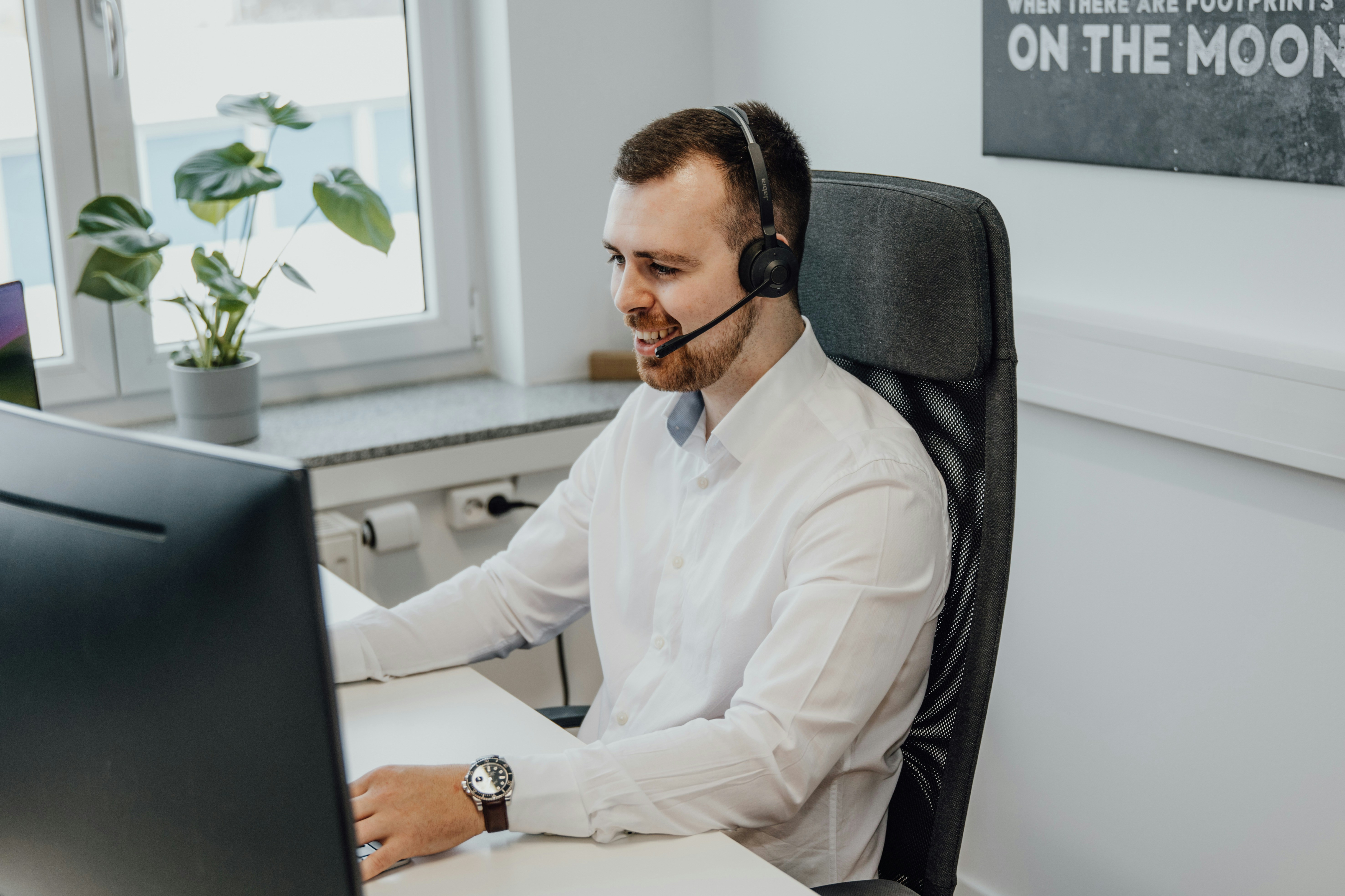 Professional male customer service agent wearing a headset, engaging in a customer support interaction with a friendly and attentive demeanor.
