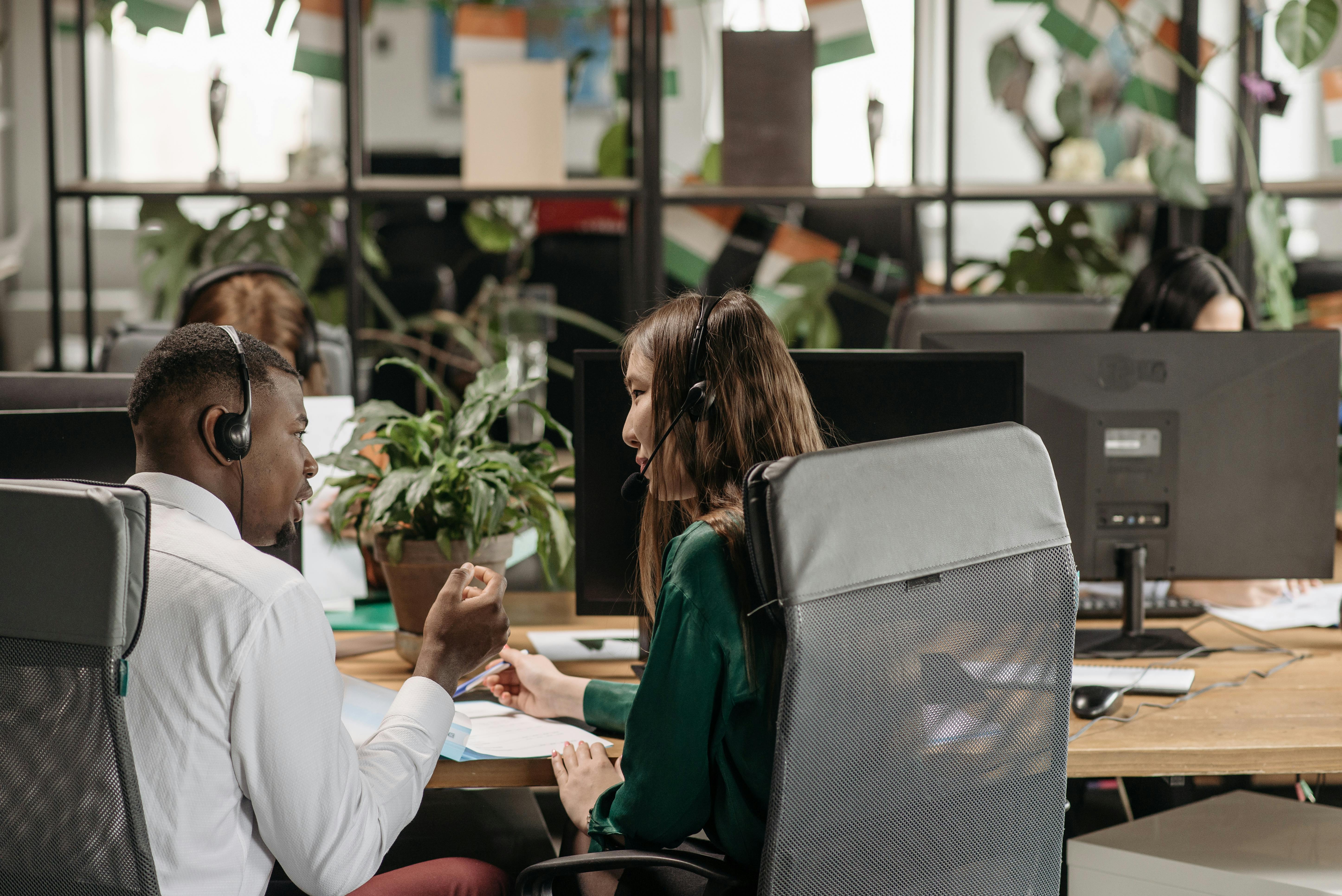 A man and a woman engaged in a professional conversation in a modern office setting, symbolizing collaboration and positive customer service interactions.