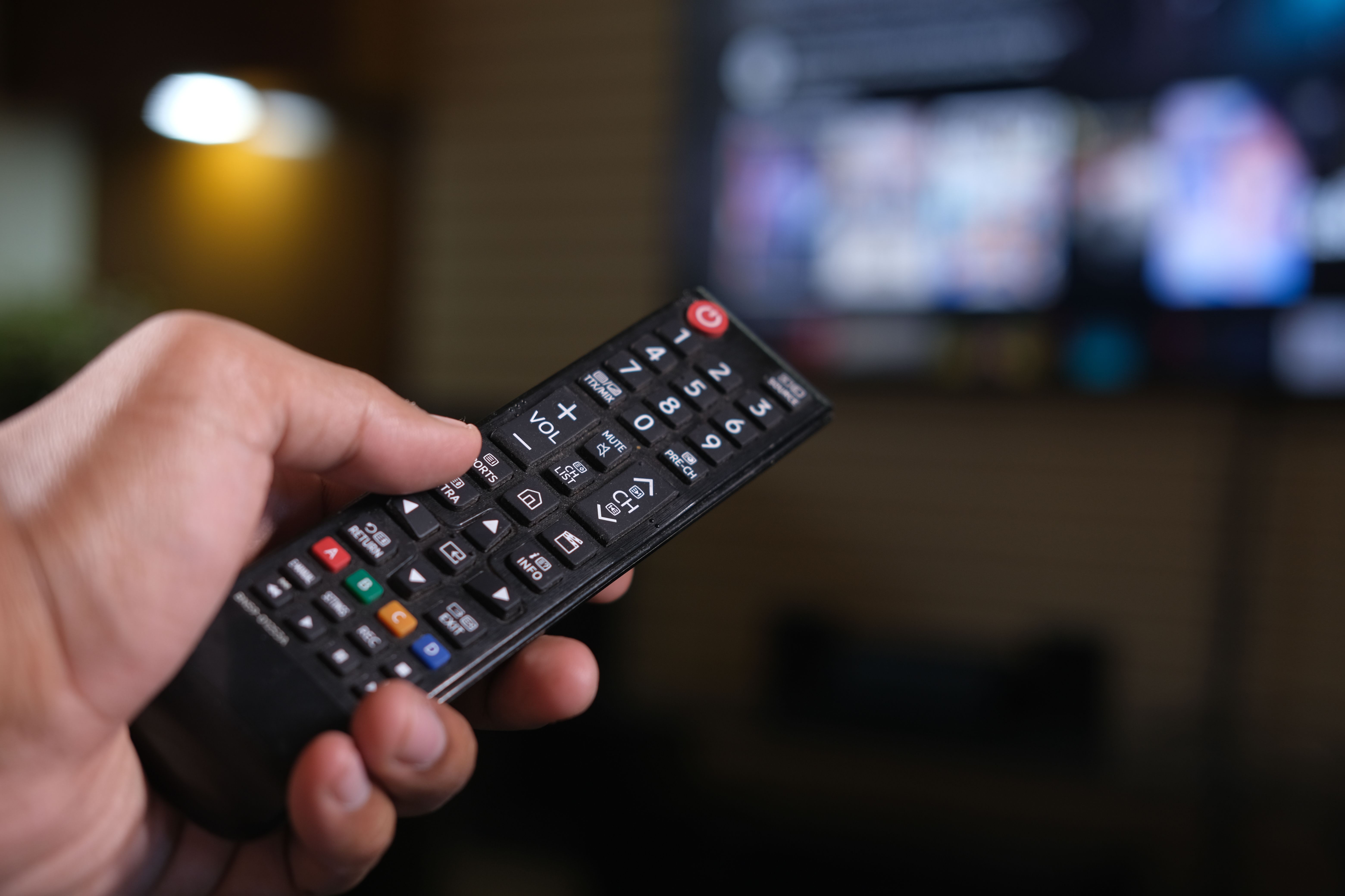A person holding a black remote control, symbolizing control and decision-making, aligning with themes of leadership, communication, and transformation.