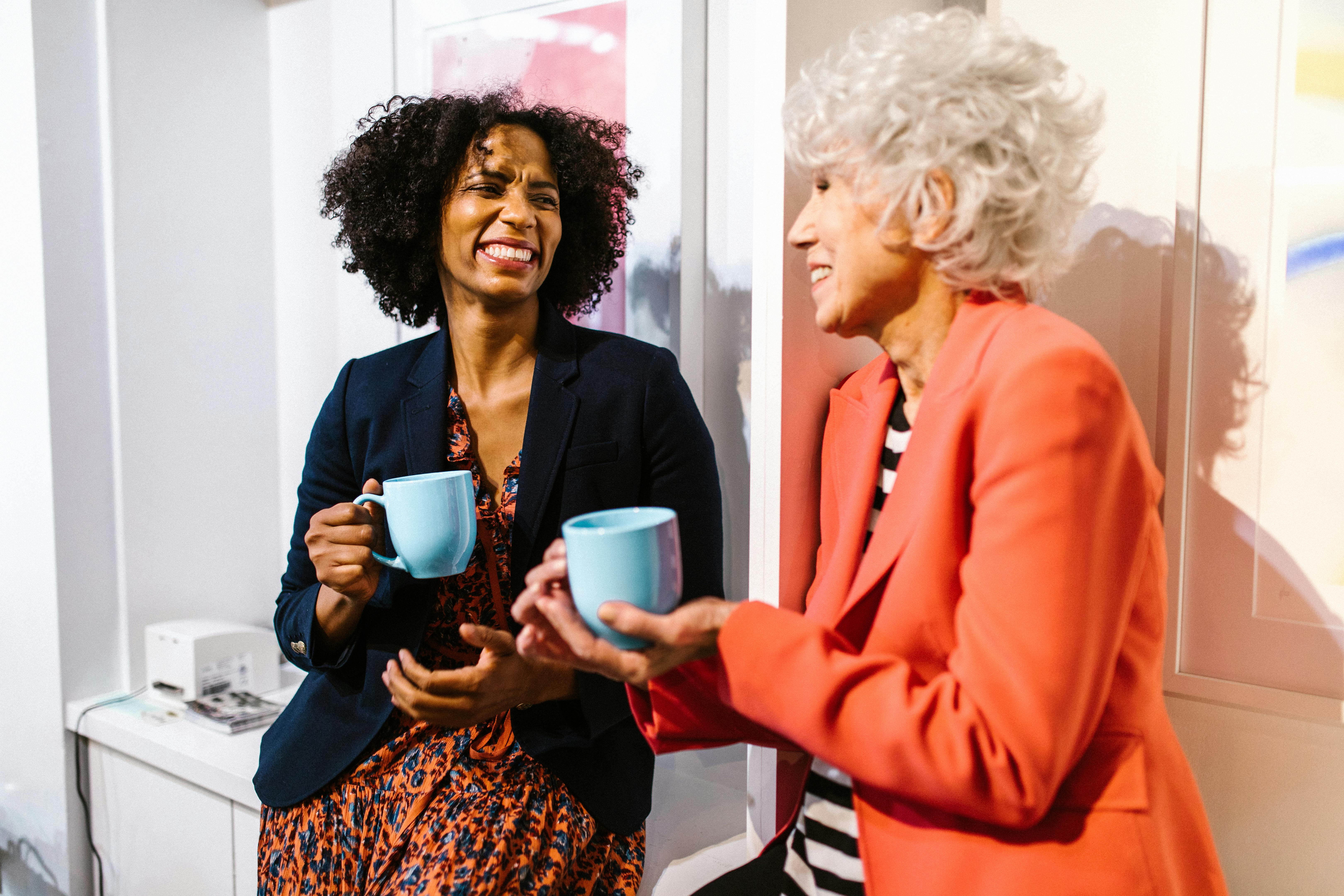 Professional woman in an orange blazer holding a blue ceramic mug, symbolizing reflection, networking, and meaningful connections in career growth.