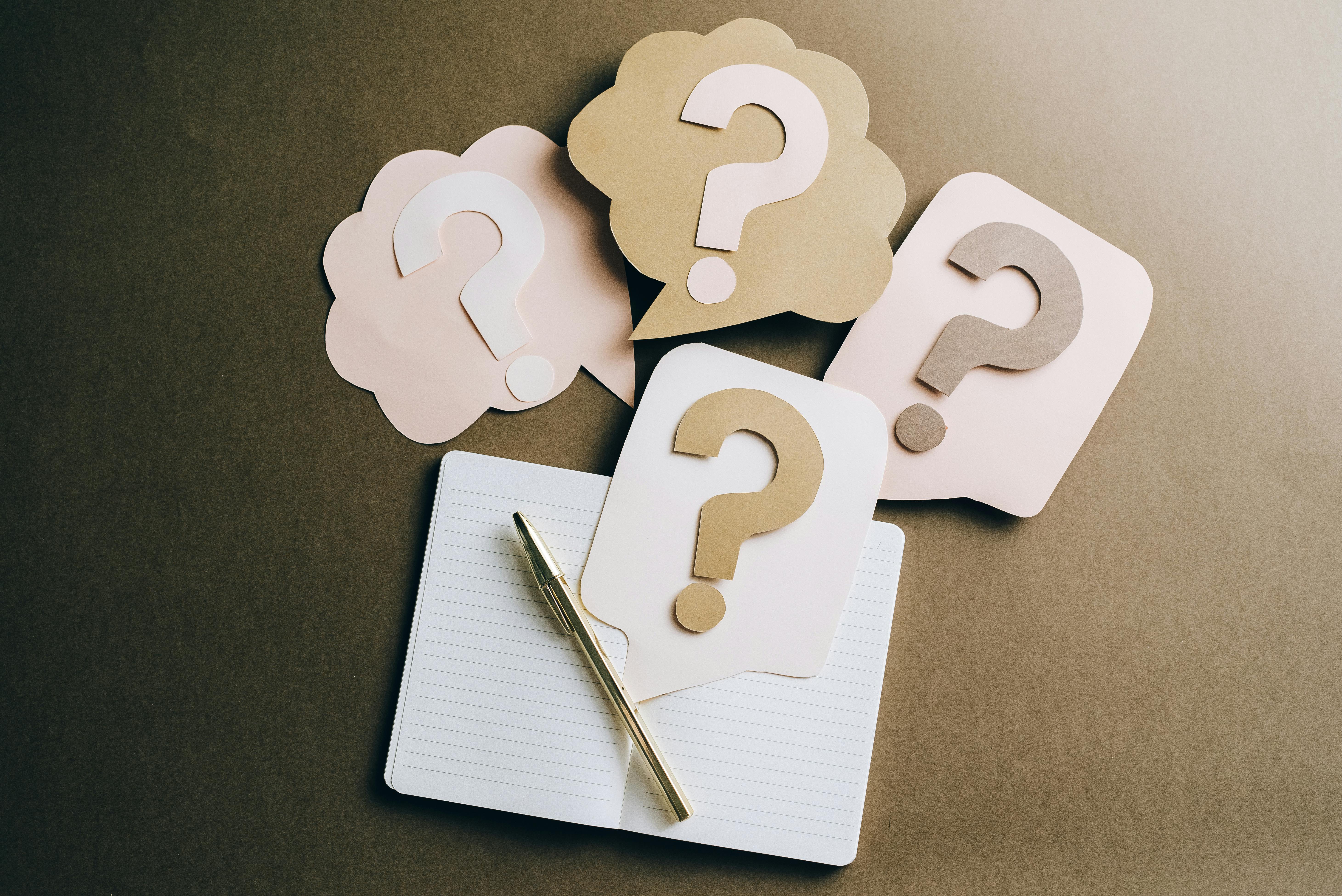 A close-up of multiple black question marks printed on brown craft paper, symbolizing confusion or inquiry.