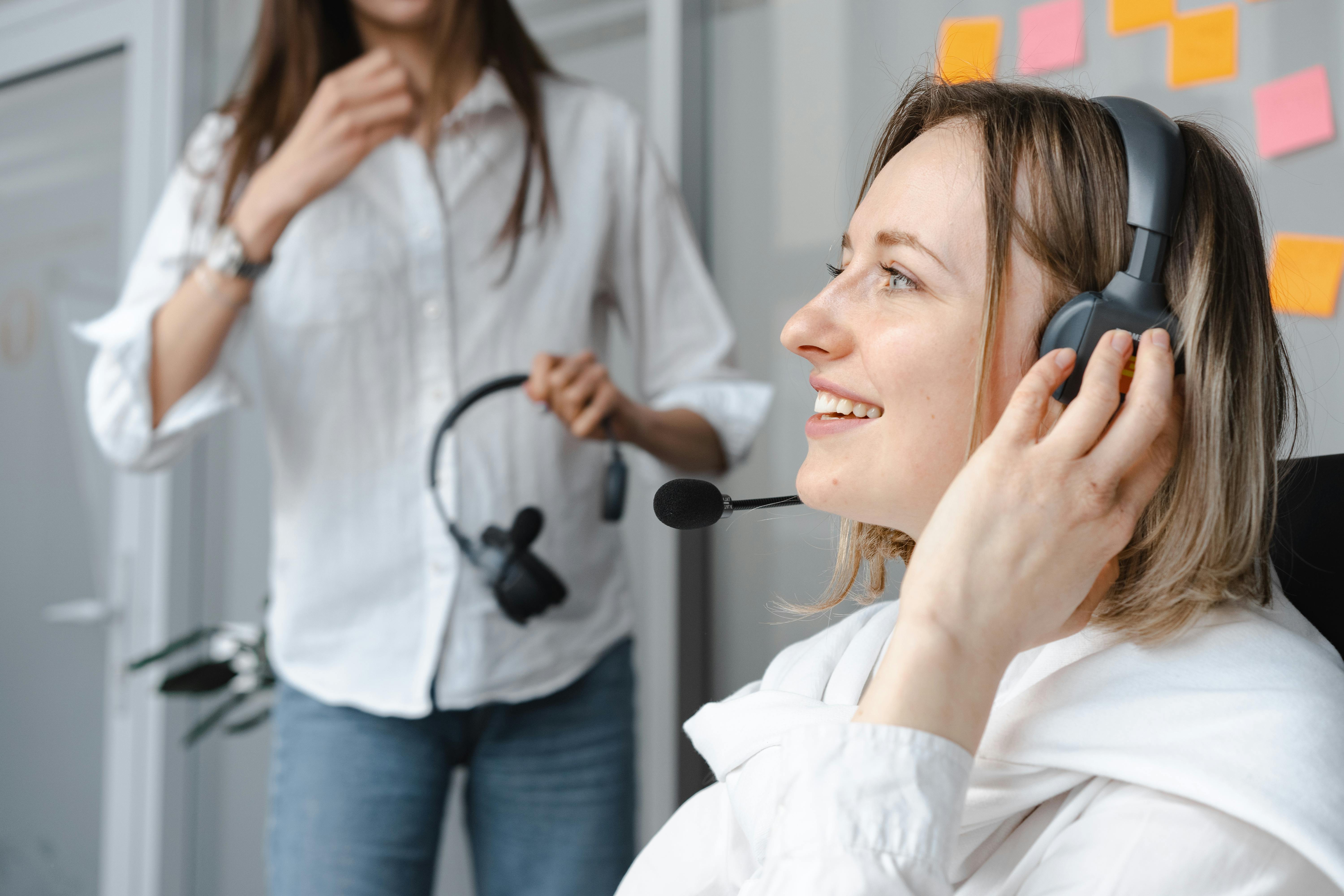 Close-up of a smiling woman wearing headphones, representing a positive and professional contact center environment.