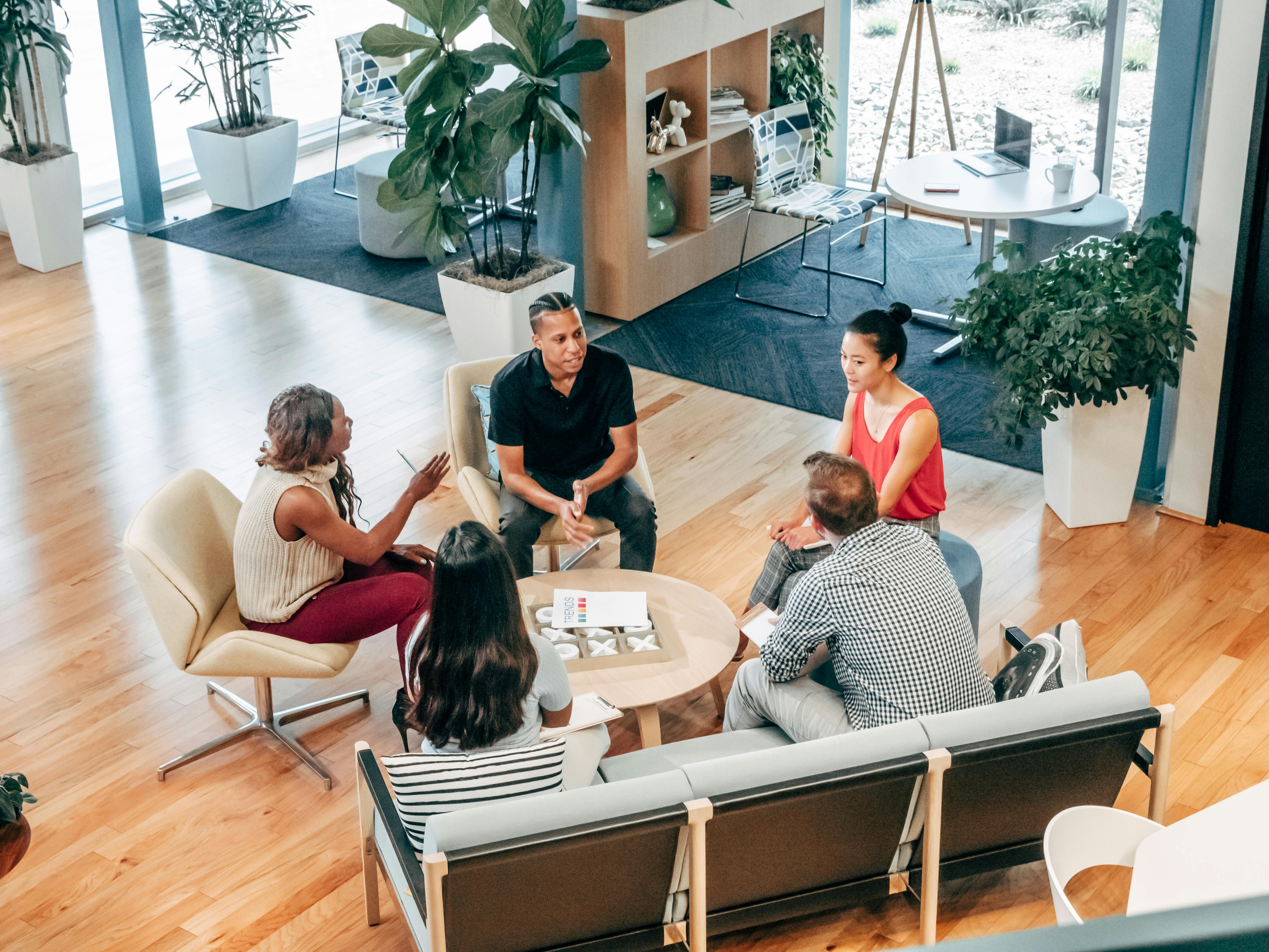 A group of people sitting around a table in a professional setting, engaged in a team discussion and collaboration.