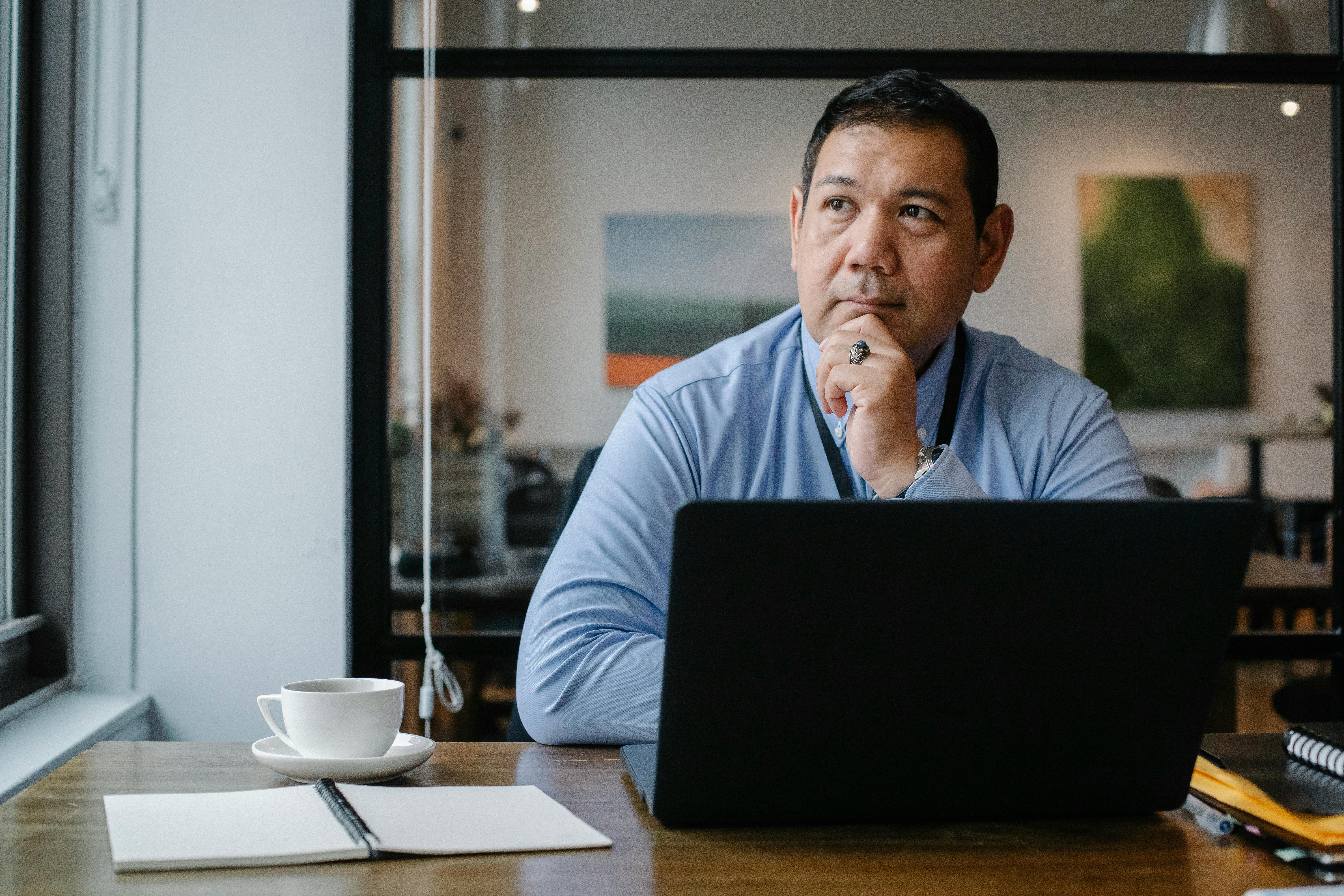 Thoughtful ethnic businessman using a laptop while working in a modern office environment