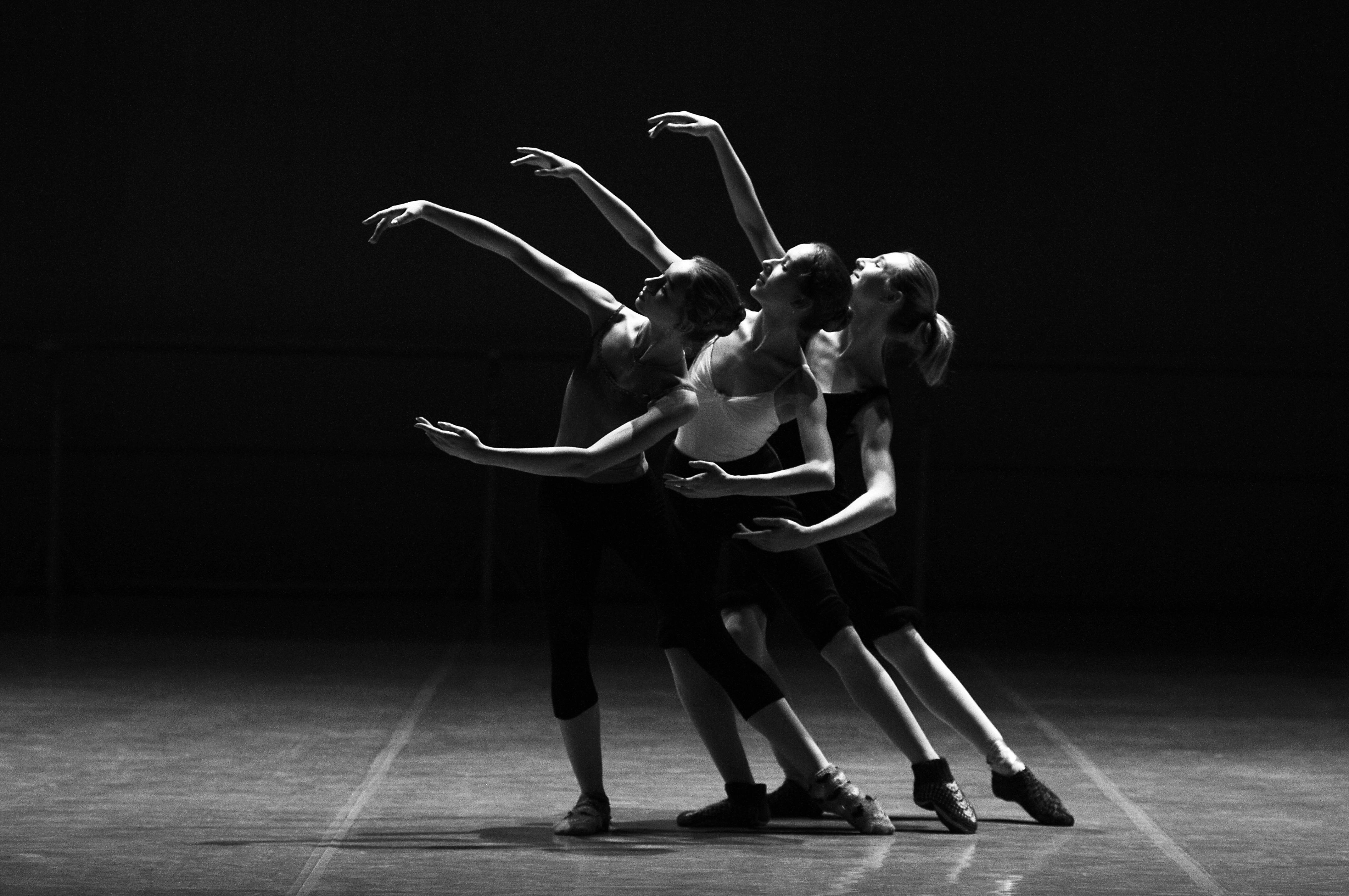 Three female ballet dancers gracefully performing on stage, showcasing elegance, skill, and artistry in motion.