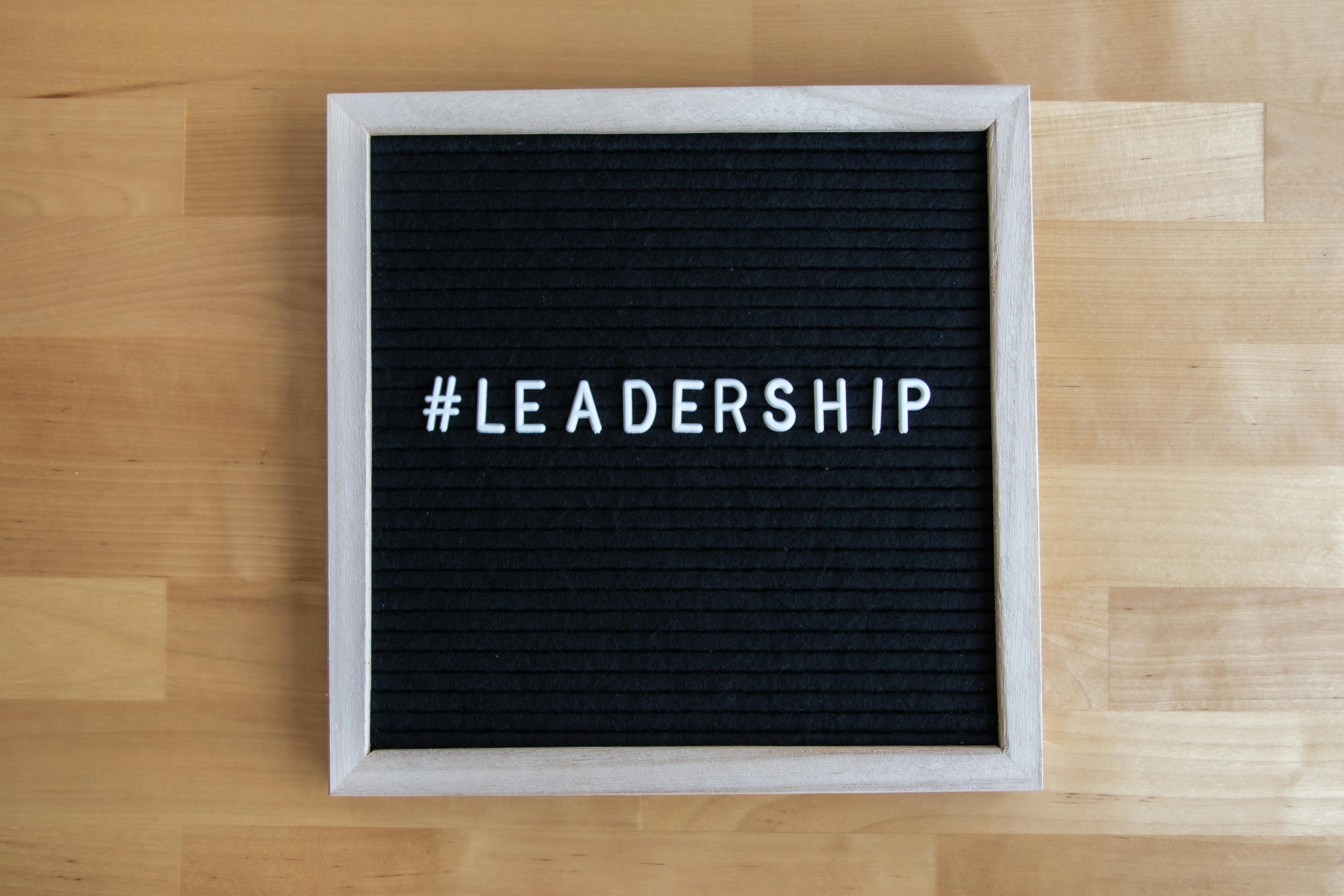 Black letter board with white text reading "Transformational Leadership" placed on a wooden surface, symbolizing leadership principles and inspiration.