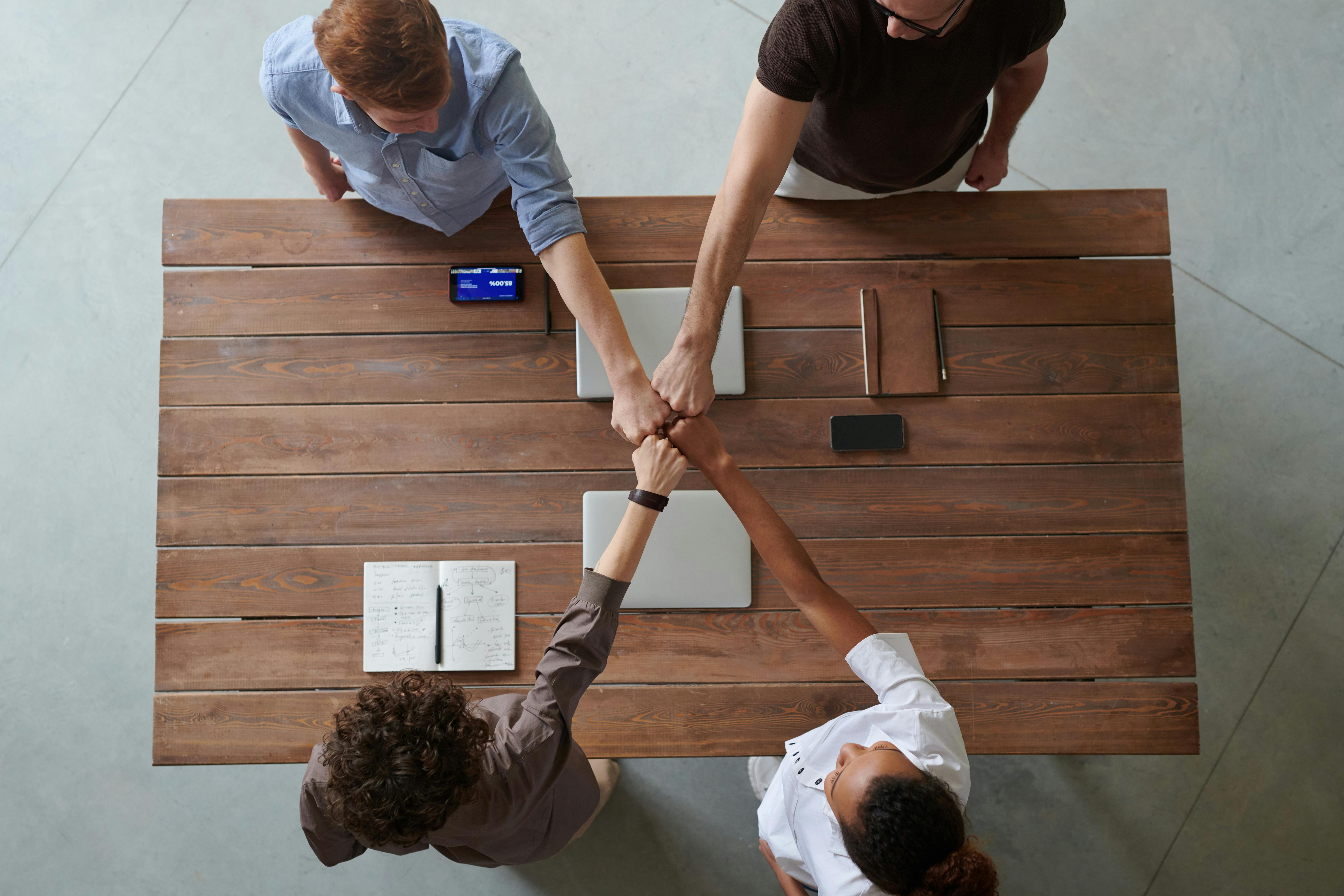 Group of colleagues doing a fist bump, symbolizing teamwork, collaboration, and mutual support in a professional setting.