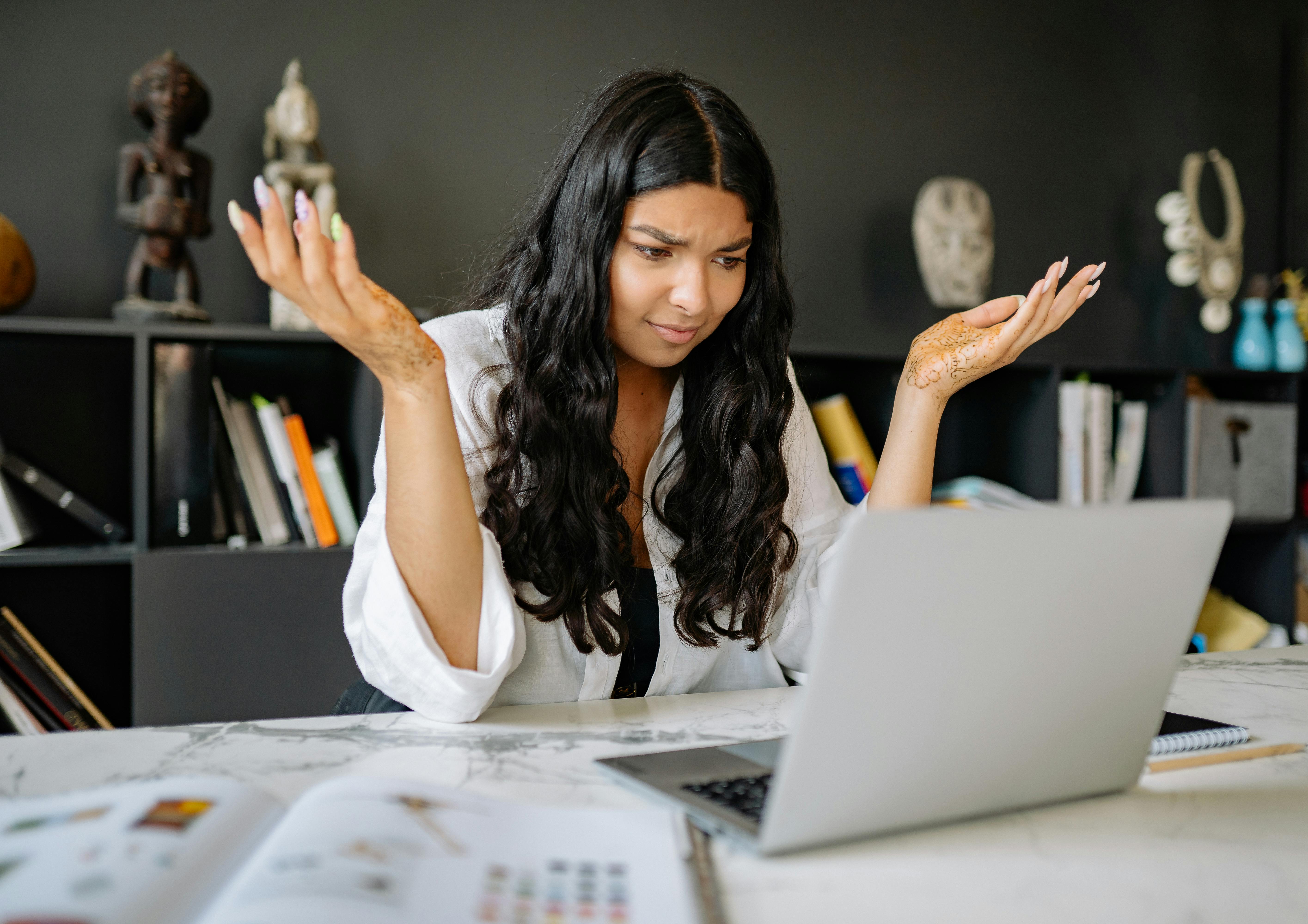 A woman in white long sleeves using a laptop, representing contact center AI deployment and implementation strategies.