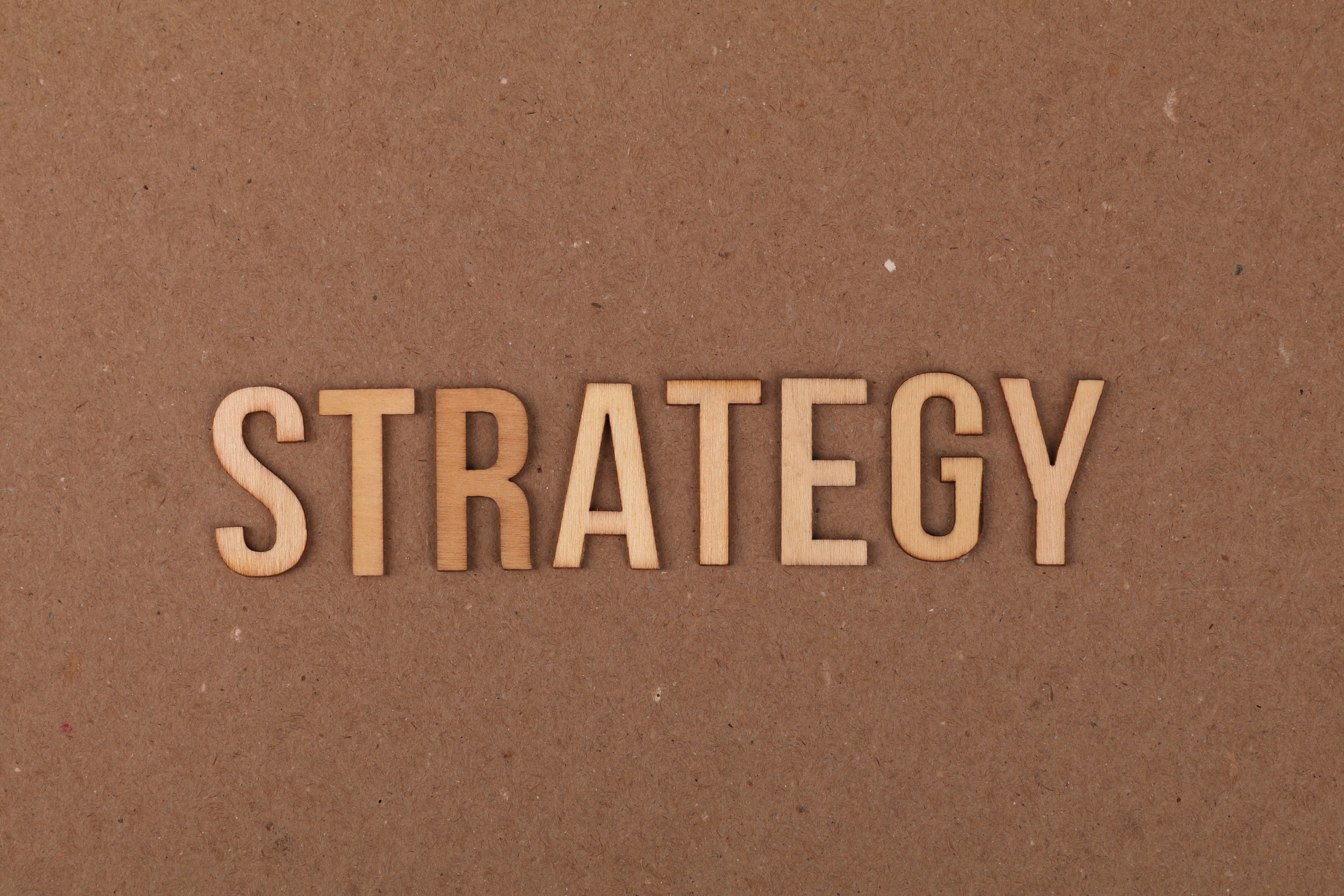 Wooden letters spelling 'strategy' on a cardboard surface, symbolizing the integration of artificial intelligence in customer experience strategies.