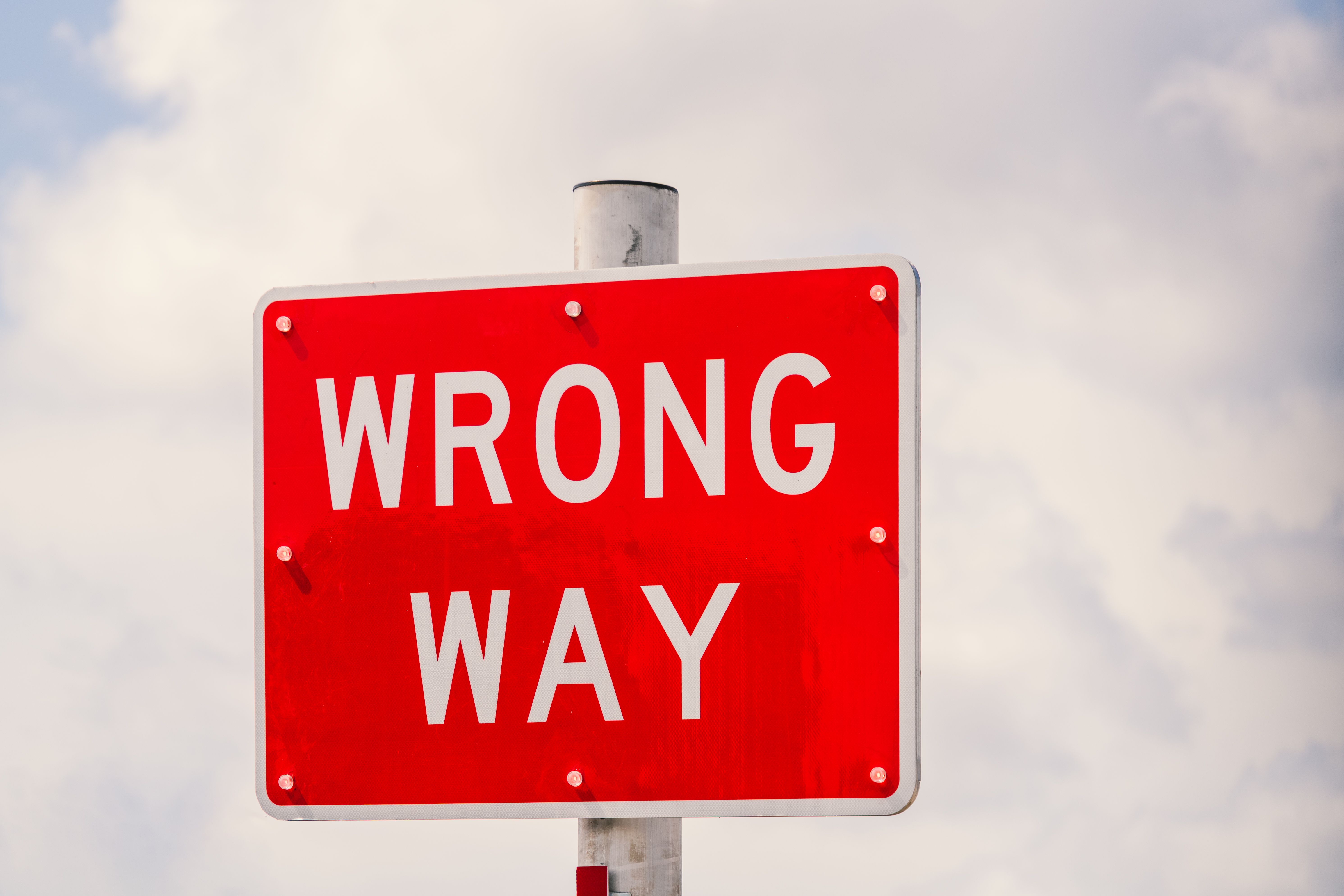 Bright red 'Wrong Way' traffic sign in Miami, symbolizing misdirection and the importance of reevaluating priorities.